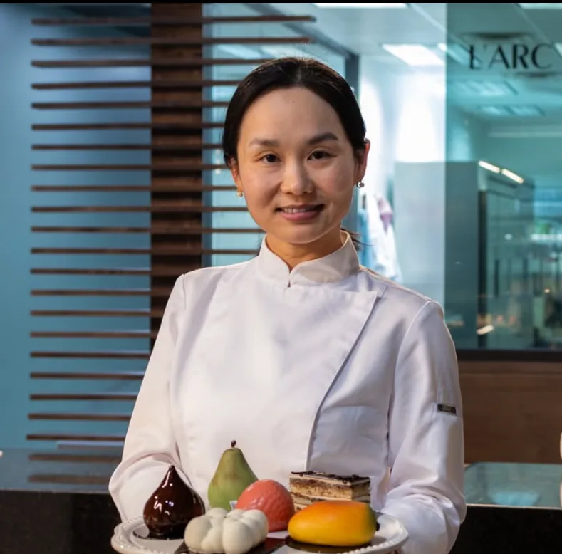 Chef Isabella in her whites, holding a tray of trompe-l'œil pastries